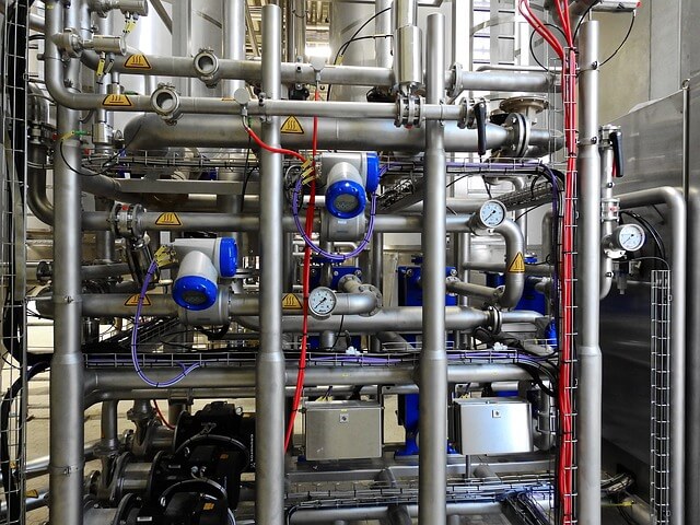 Complex network of industrial pipes and valves in a mechanical room.