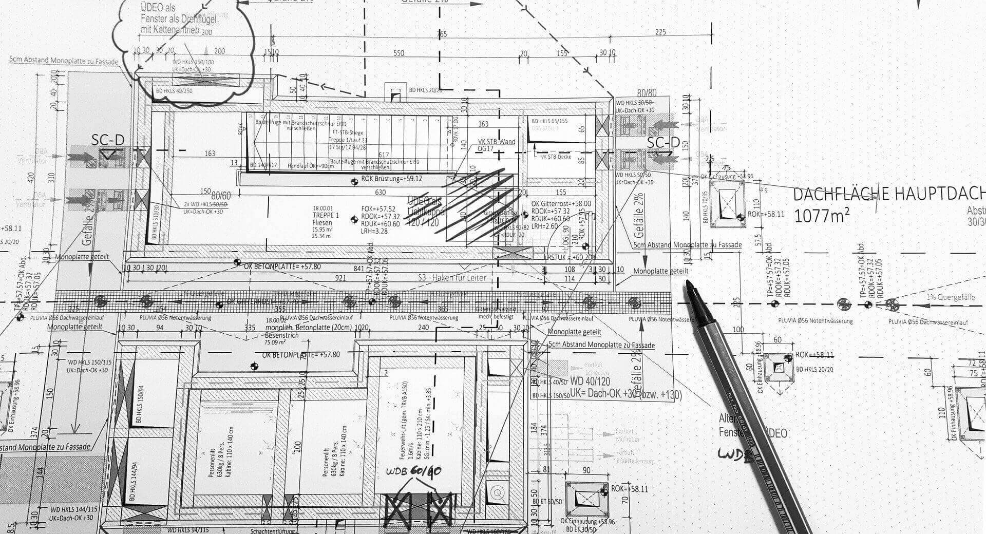 Arkitektonisk ritning med anteckningar och en penna som indikerar aktiv planering eller granskning.