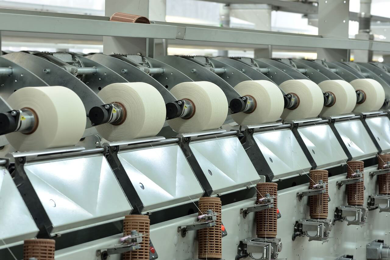 Textile machinery with multiple spools of thread during the yarn spinning process.