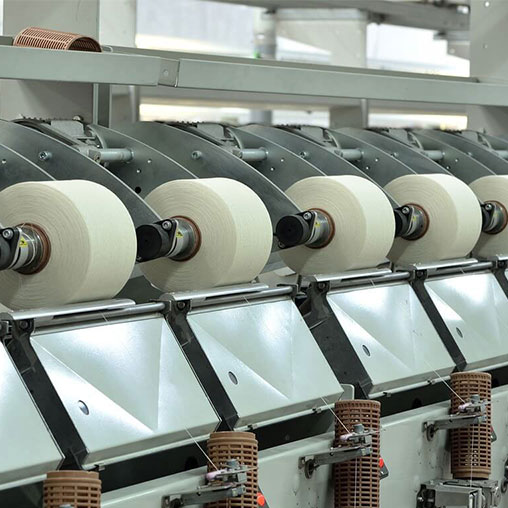 Garn som bearbetas på industriella spinnmaskiner i en textilfabrik.