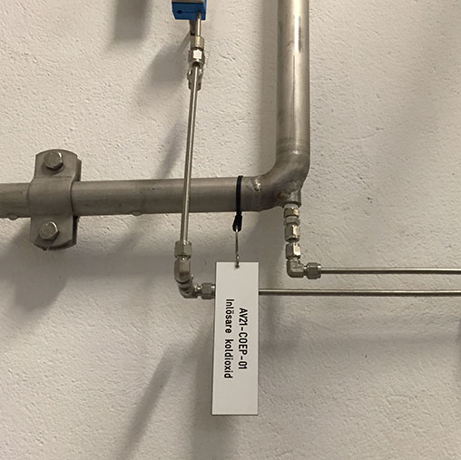 Metallrör på vägg med en ventil märkt "luftkomp. inlopp - hästkrafter låst".